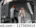 Explore the behindthescenes of a fashion photoshoot in a studio with a model and photographer 117369414