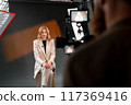 A professional woman wearing a business suit is being filmed in a studio setting 117369416