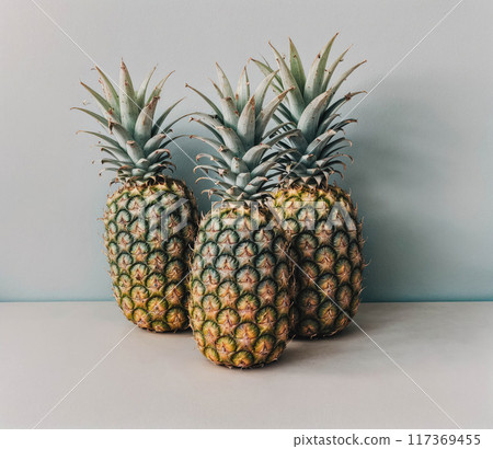 Three pineapples are sitting on a table 117369455