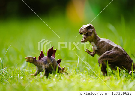 Child playing with dinosaur toy in sunny garden Child playing with dinosaur toy in sunny garden 117369622