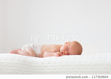 Little baby on white bed 117369664