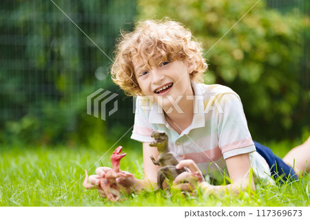 Child playing with dinosaur toy in sunny garden 117369673