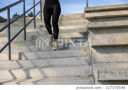 Woman in black sportswear going downwards on the steps Woman in black sportswear going downwards on the steps 117370599