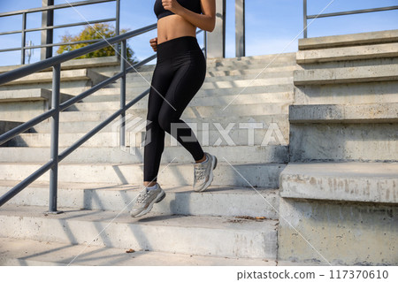 Woman in black sportswear going downwards on the steps 117370610