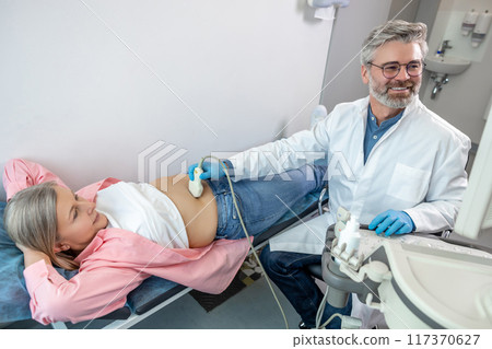 Male doctor looking focused while making diagnostics to a female patient 117370627