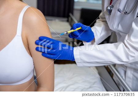 Doctor in sterile gloves making an injection to the arm of a pregnant woman 117370635