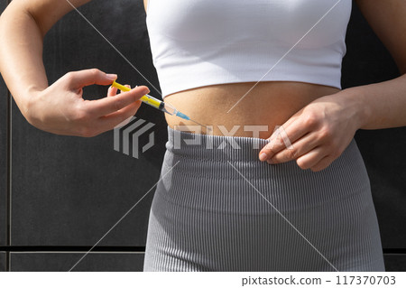 Close up of a woman doing lipolytic injection to her abs 117370703