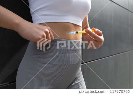 Close up of a woman doing lipolytic injection to her abs 117370705