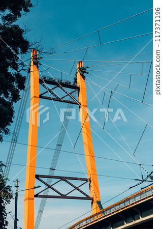 A large orange bridge with a blue sky in the background 117371196