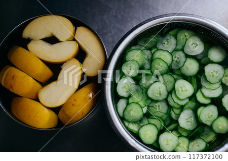 Sliced cucumber and sliced apple for potato salad 117372100