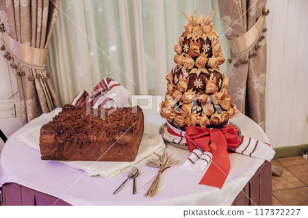 Delicious sweet wedding loaf, cake in the Ukrainian style on embroidered towels. Festive sweet table 117372227