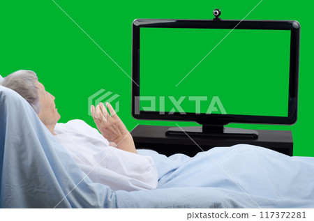 Pale Senior Woman Communicates via Green Screen Monitor from Hospital Bed, Engaging in Telemedicine or Virtual Family Visit. Pale Senior Woman Communicates via Green Screen Monitor from Hospital Bed, Engaging in Telemedicine or Virtual Family Visit. 117372281