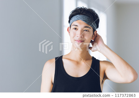 Young man wearing a hair band looking in the mirror Young man wearing a hair band looking in the mirror 117372863