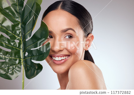 Happiness is having natural beauty. Studio shot of a beautiful young woman posing with a leaf against a grey background. Happiness is having natural beauty. Studio shot of a beautiful young woman posing with a leaf against a grey background. 117372882