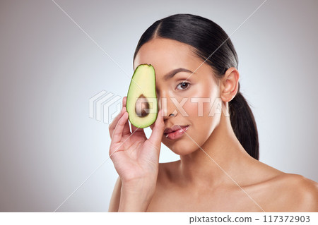 Hydrate and moisturise your skin with avocado. Studio portrait of a beautiful young woman posing with an avocado against a grey background. 117372903