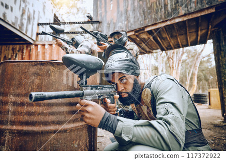 Paintball, black man and game, gun and target, sport with fitness and battlefield challenge, war and soldier outdoor. Extreme sports, exercise at shooting range and military team with mission 117372922