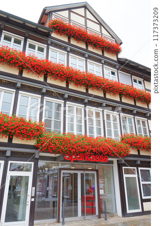 A cute half-timbered house decorated with red flowers A cute half-timbered house decorated with red flowers 117373209