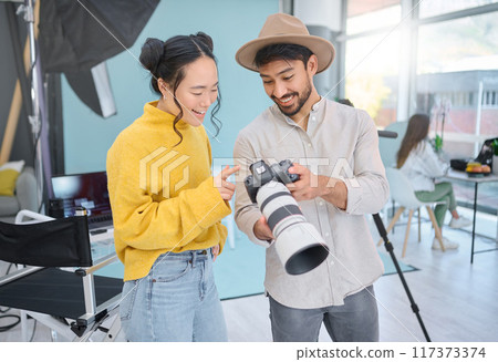 Camera, creativity and photographer talking to a model while looking at pictures from a photoshoot. Photography, creative and young cameraman choosing a image with a woman in creative artistic studio Camera, creativity and photographer talking to a model while looking at pictures from a photoshoot. Photography, creative and young cameraman choosing a image with a woman in creative artistic studio 117373374