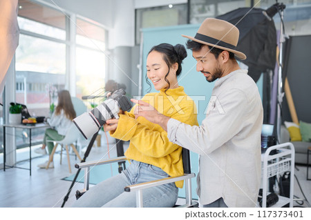 Photography, creative and man talking to a model to choose a image on the camera from the photoshoot. Creativity, art and male photographer speaking to a woman for the best picture in artistic studio Photography, creative and man talking to a model to choose a image on the camera from the photoshoot. Creativity, art and male photographer speaking to a woman for the best picture in artistic studio 117373401