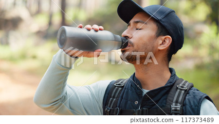 Hiking, forest and man drinking water in nature, park or woods for outdoor fitness, health and training. Young person with liquid bottle for nutrition, tired and exercise break for travel or trekking Hiking, forest and man drinking water in nature, park or woods for outdoor fitness, health and training. Young person with liquid bottle for nutrition, tired and exercise break for travel or trekking 117373489