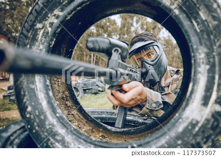 Gun aim at target with tire, paintball and man outdoor, action on battlefield and soldier focus during war game. Extreme sport, weapon and military mission, exercise and fitness with determination Gun aim at target with tire, paintball and man outdoor, action on battlefield and soldier focus during war game. Extreme sport, weapon and military mission, exercise and fitness with determination 117373507