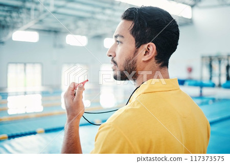 Lifeguard, whistle and swimming pool safety by man watching at indoor facility for training, swim and practice. Pool, attendant and guy water sports worker monitoring exercise, danger and swimmer Lifeguard, whistle and swimming pool safety by man watching at indoor facility for training, swim and practice. Pool, attendant and guy water sports worker monitoring exercise, danger and swimmer 117373575