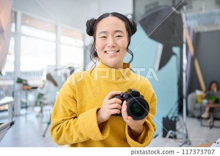 Smile, camera and portrait of a photographer working at a studio for a photoshoot. Happy, media and creative Asian woman shooting, filming or learning about photography production as a career Smile, camera and portrait of a photographer working at a studio for a photoshoot. Happy, media and creative Asian woman shooting, filming or learning about photography production as a career 117373707