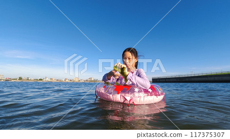 仲夏時節,一名小學生在海灘上用漂浮物在水中玩耍 仲夏時節,一名小學生在海灘上用漂浮物在水中玩耍 117375307