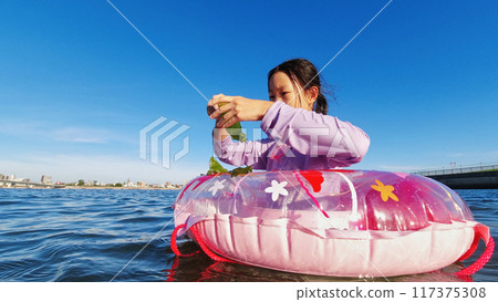 仲夏時節,一名小學生在海灘上用漂浮物在水中玩耍 仲夏時節,一名小學生在海灘上用漂浮物在水中玩耍 117375308