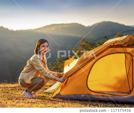 Image of a woman setting up a tent 117375438