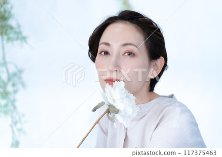 Middle-aged woman holding a white rose 117375463