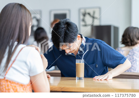 Young man apologizing to his girlfriend in a cafe Young man apologizing to his girlfriend in a cafe 117375780