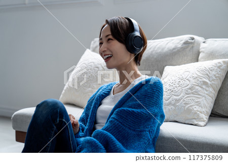 Middle woman listening to music in the living room 117375809