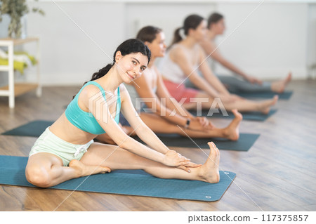 Sporty girl doing stretching in Janu Sirsasana in yoga studio 117375857