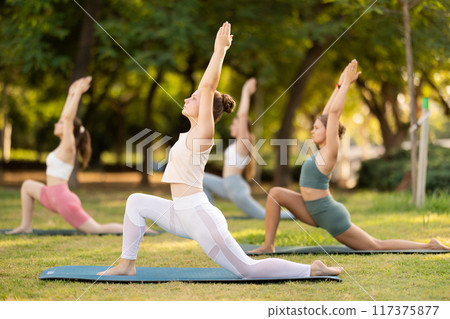 Yoga lesson visitors girls perform ardha virabhadrasana in park 117375877