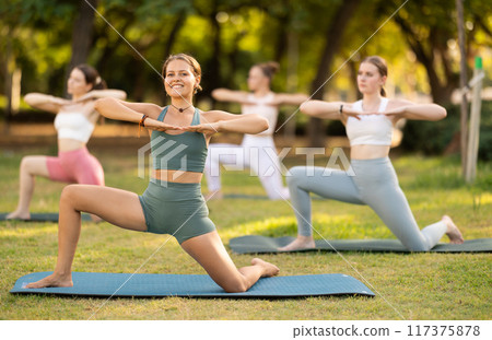 Group of young women doing yoga in park 117375878