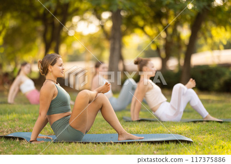 Group of young women doing stretching in park Group of young women doing stretching in park 117375886