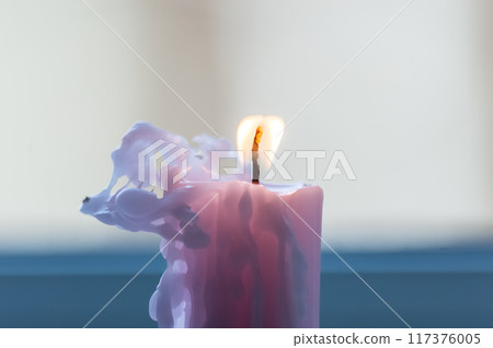 Burning candle in the form of a flower on a blue background 117376005