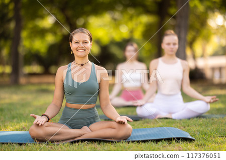 Lotus pose - young pretty girls doing yoga outdoors 117376051