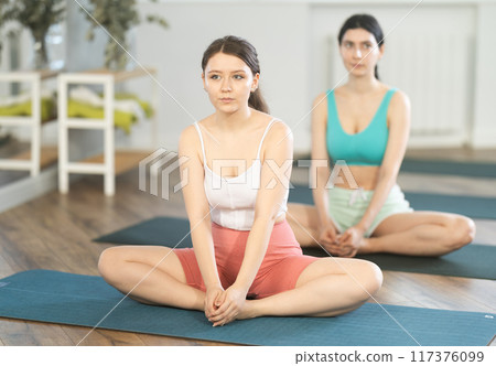 Young girl practicing Baddha Konasana at group yoga session Young girl practicing Baddha Konasana at group yoga session 117376099
