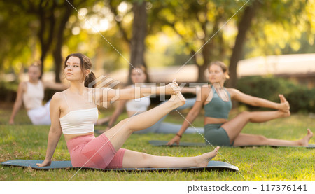 Yoga lesson visitors girls perform eka padahastasana salamba navasana in park 117376141