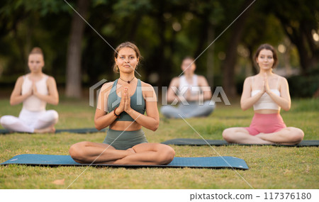 Yoga lesson visitors girls perform padmasana in park Yoga lesson visitors girls perform padmasana in park 117376180