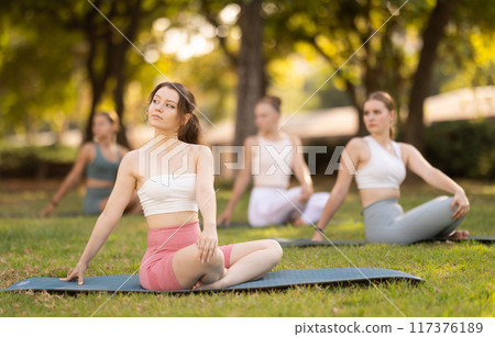 Yoga lesson visitors girls perform padmasana in park Yoga lesson visitors girls perform padmasana in park 117376189