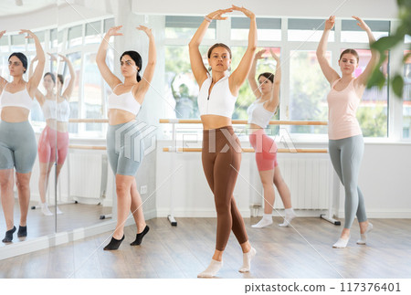 Group of oung ballerinas rehearsing ballet movements in the choreography studio Group of oung ballerinas rehearsing ballet movements in the choreography studio 117376401