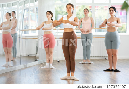 Young girl practicing ballet positions standing in row with others Young girl practicing ballet positions standing in row with others 117376407