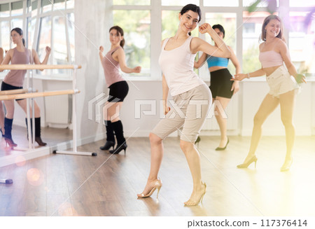 During lesson, girl learn to move and perform dance in heels with women companions 117376414