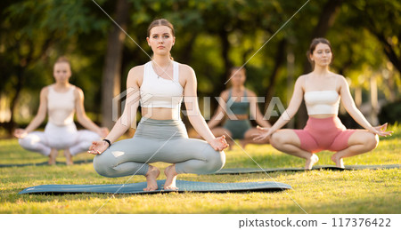 Yoga lesson visitors girls perform prapadasana in park 117376422