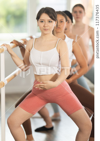 Young ballerinas practicing demi plie at barre in choreography studio 117376435