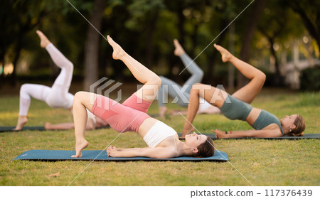 Athletic girls leading an active lifestyle, training in a summer park, performing dynamic asanas to improve body flexibility Athletic girls leading an active lifestyle, training in a summer park, performing dynamic asanas to improve body flexibility 117376439