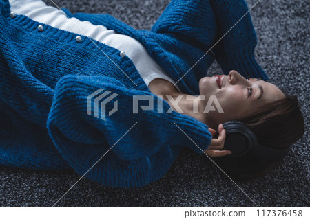 一位中年婦女躺在地毯上沉浸在音樂中 117376458